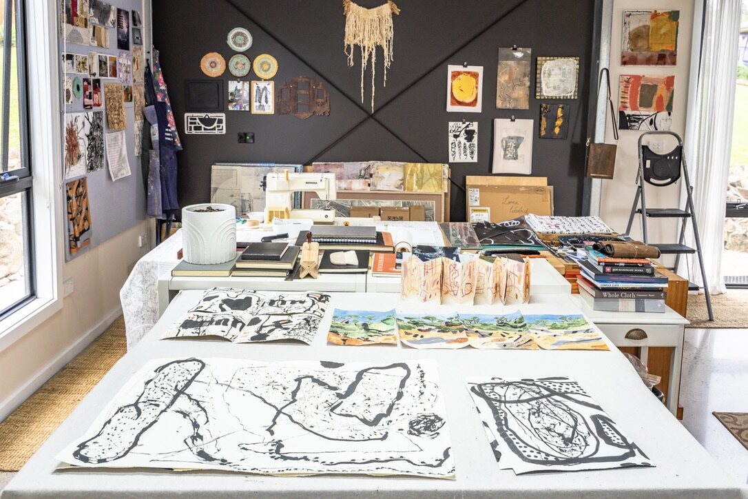 Lorna Crane studio worktable with ink drawings, paper studies, books and studio materials