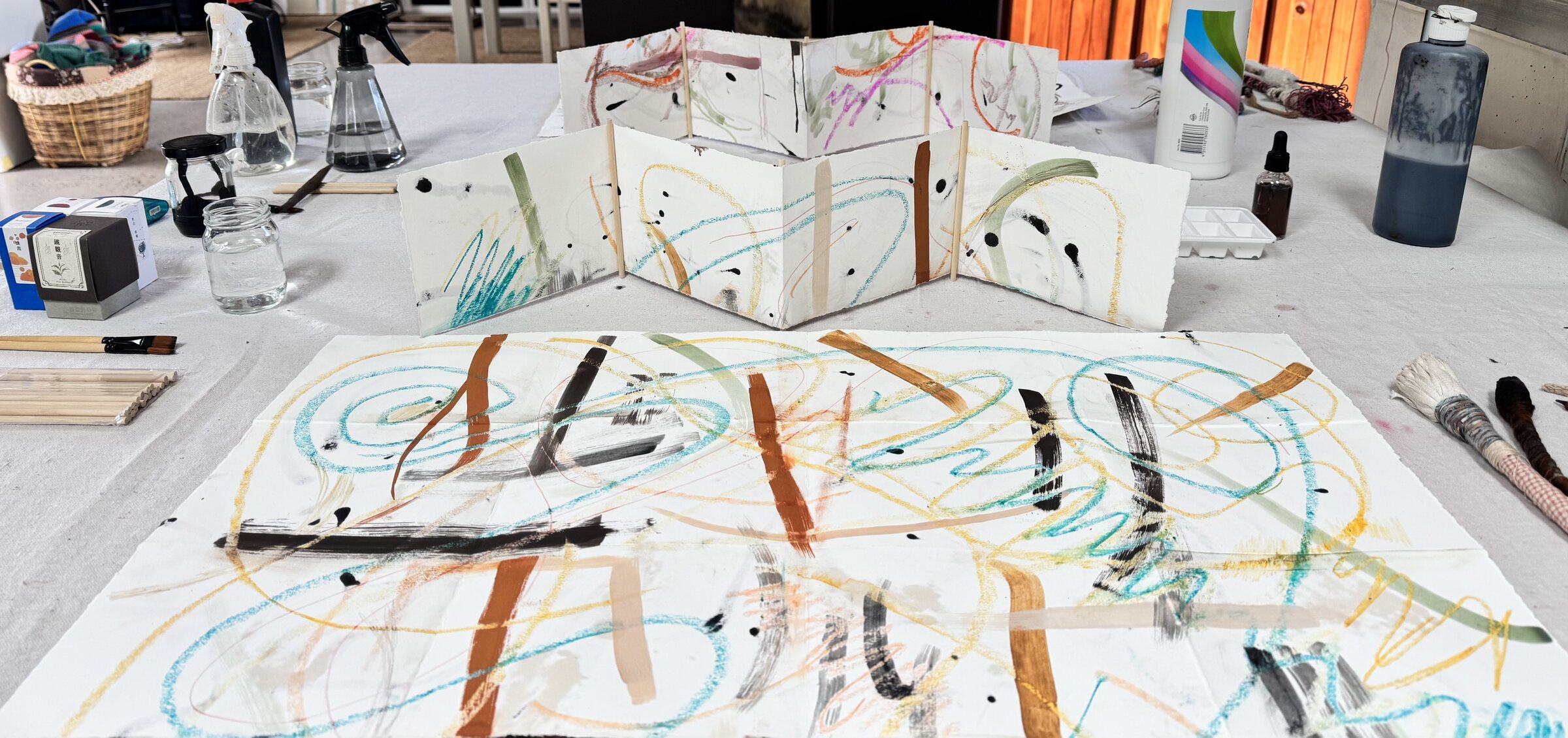 Colourful concertina artist book and large gestural paper study on a studio table