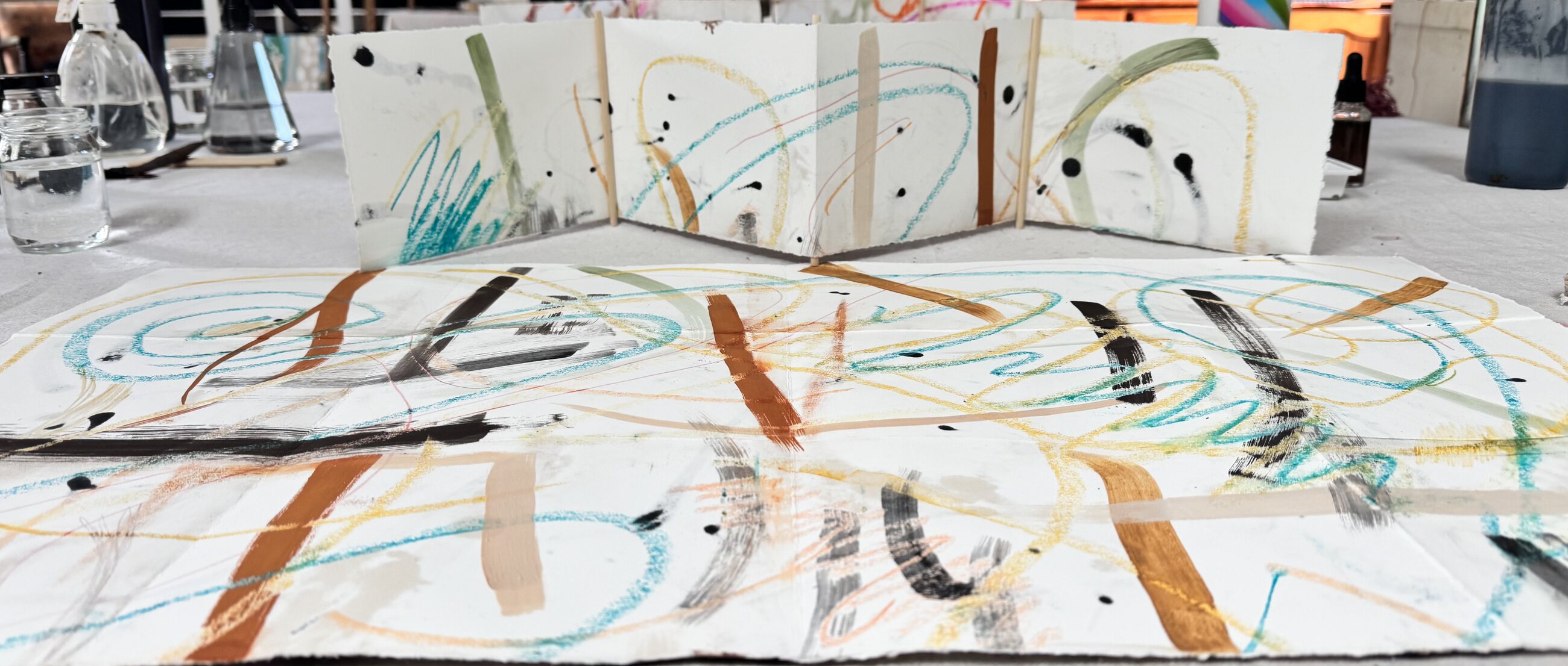 Wide view of colourful abstract session work with folded paper studies in the studio