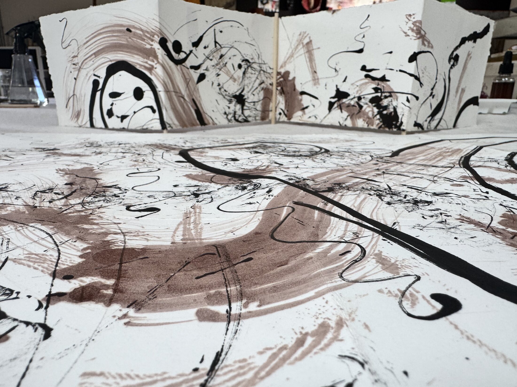 Close view of folded ink and earth pigment studies standing on a studio table