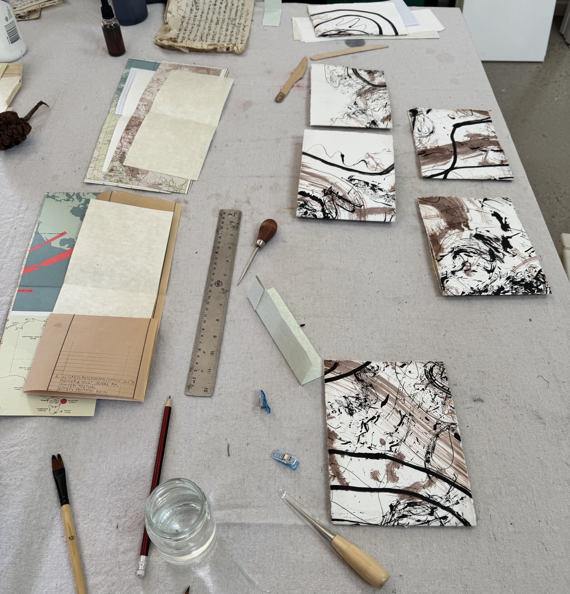 Ink studies, brushes, pencil, ruler and paper materials arranged on a studio work table