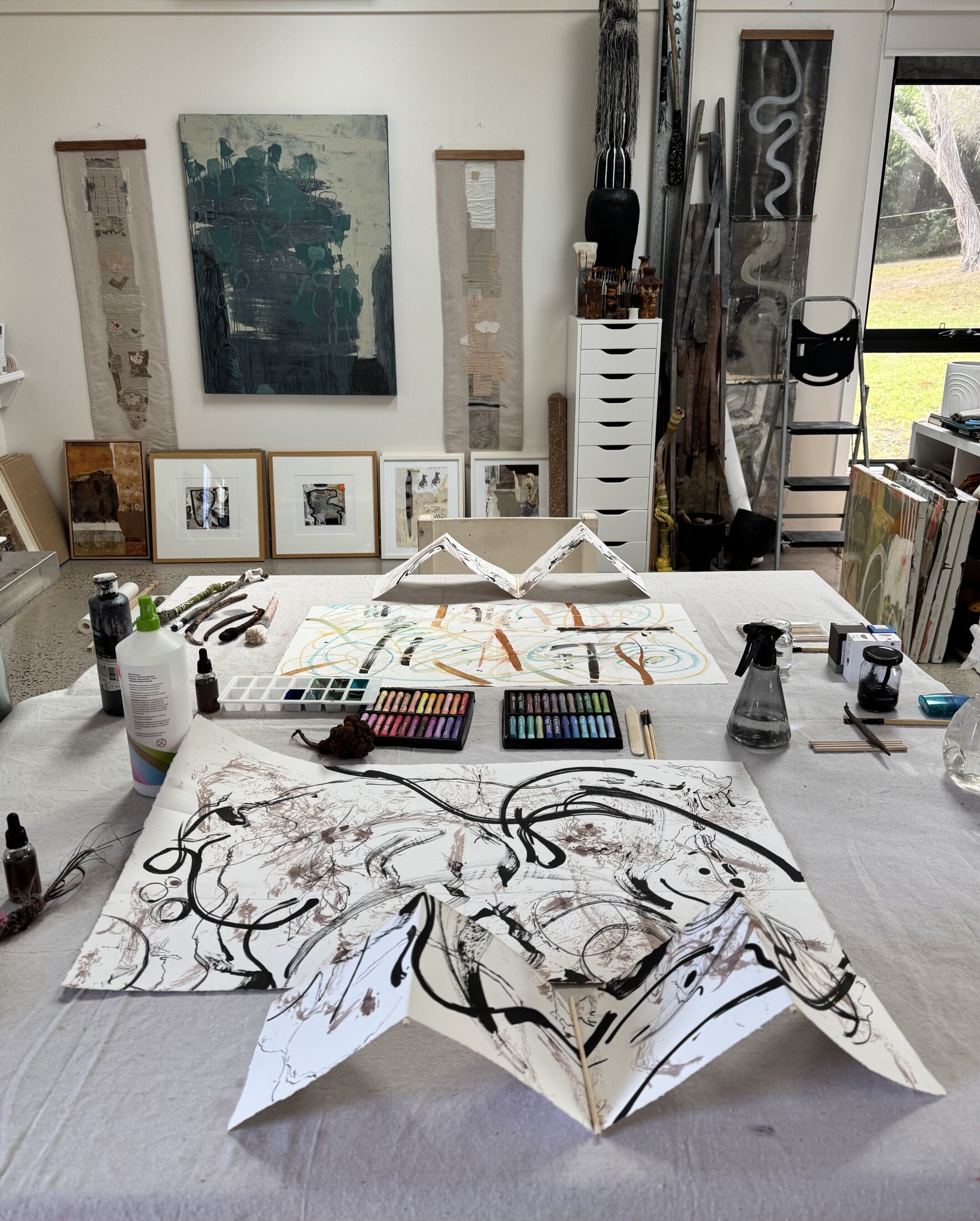 Lorna Crane studio table prepared for an abstract art session with paper works, pastels and tools